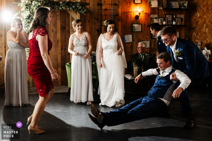 Fotografia documental do local do casamento Little Wold Vineyard em Yorkshire mostrando o noivo pega seu padrinho caindo durante a dança na recepção do casamento