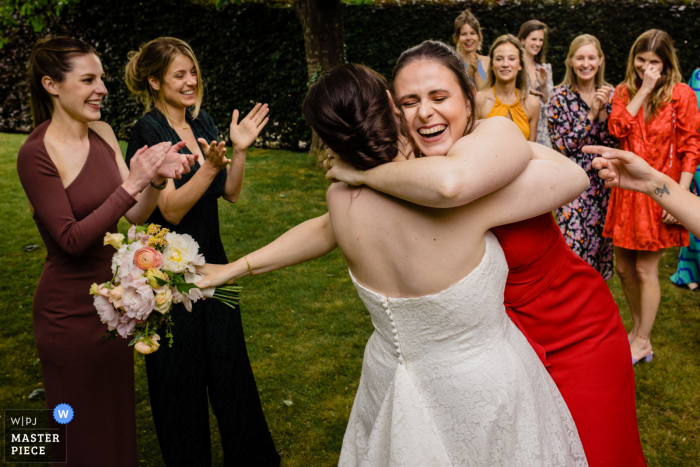 Photographie de mariage et d'événement basée à Park West en Belgique montrant la mariée étreignant une femme après le lancer du bouquet à l'extérieur