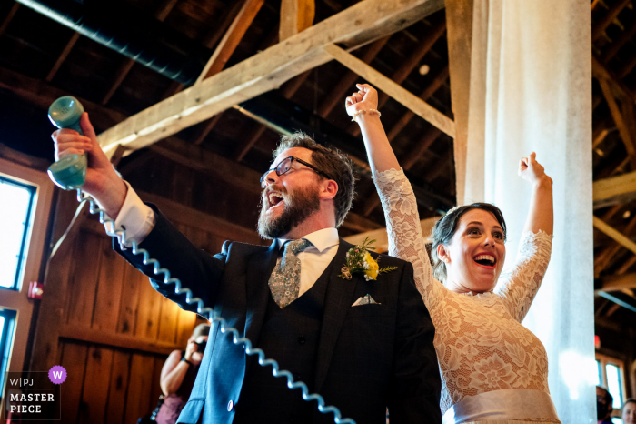 Trouw- en evenementfotografie in Vermont in The Barn at Boyden Farm vastgelegd terwijl de bruid en bruidegom een ​​bericht voor zichzelf achterlaten op een telefoon om later naar te luisteren bij het betreden van de receptie