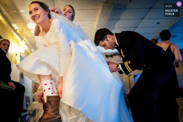 La fotografía del lugar de celebración de bodas del Equinox Resort en Vermont creada cuando la novia se pone las botas mientras el novio avienta su vestido y la dama de honor arregla su velo