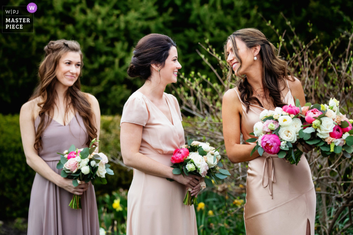 Il fotografo di matrimoni documentaristici presso la sede dell'evento The Farmhouse a Hampton, nel New Jersey, ha catturato la damigella d'onore guardando indietro alla damigella d'onore e sorridente