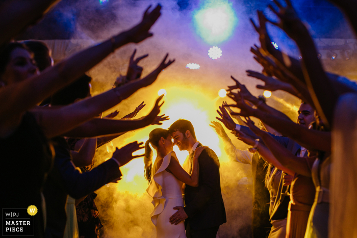 Fotografie des Hochzeitsortes Osteria Val de Buia, die zeigt, wie Braut und Bräutigam mit Gästen um sie herum mit Nebel tanzen