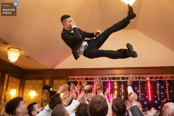 Trouwlocatiefotografie in Polen met de vliegende bruidegom boven de gasten van het receptiefeest