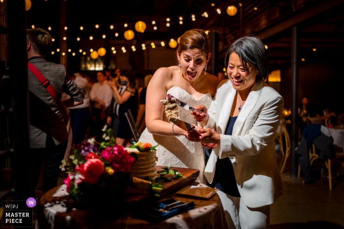 The Winslow wedding image from a Baltimore venue of The brides almost dropping their cake slice after they cut the cake