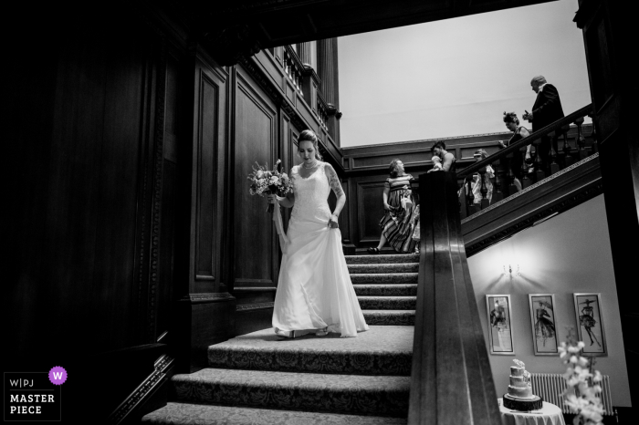 Fotografia di matrimoni ed eventi con sede a Rugby, nel Regno Unito, presso la Bourton Hall di BW of Bride mentre scende le scale