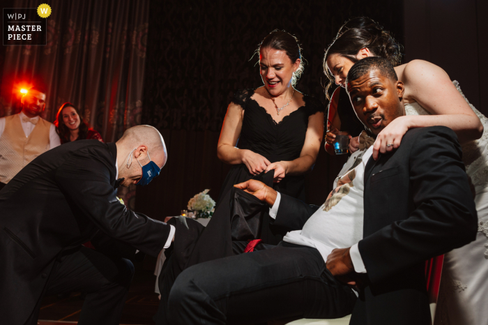 Documentary wedding photographer at the Hotel Monaco event venue in downtown Philadelphia showing what an Improvised garter removal looks like Documentary wedding photographer at the Hotel Monaco event venue in downtown Philadelphia showing what an Improvised garter removal looks like