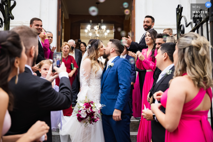 Fotografia documental de casamento premiada no concurso Petrópolis do casal se beijando na saída da cerimônia