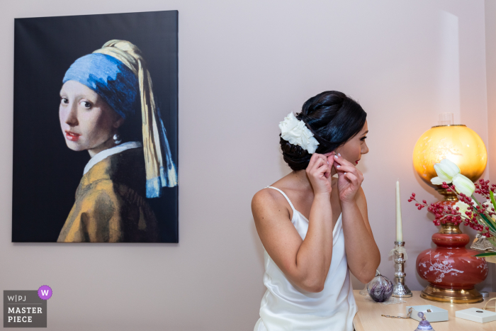 Acireale documentary wedding photography contest winning image in Italy showing This bride is putting her earrings next to a reproduction of the famous Girl with a Pearl Earring by Dutch artist Johannes Vermeer Acireale documentary wedding photography contest winning image in Italy showing This bride is putting her earrings next to a reproduction of the famous Girl with a Pearl Earring by Dutch artist Johannes Vermeer