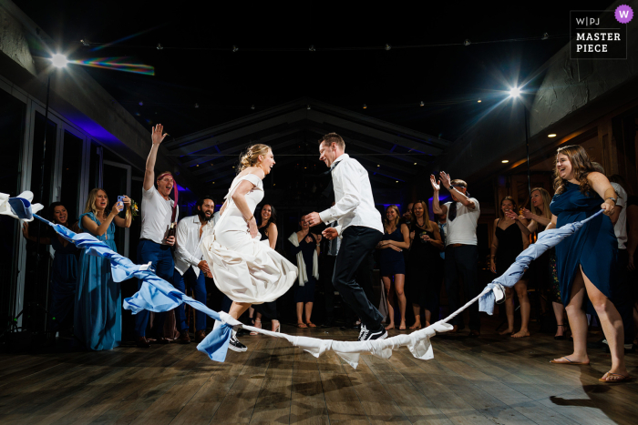 A Summit County wedding photographer captured the unique moment of a bride and groom jumping rope with napkins tied together at their night wedding venue A Summit County wedding photographer at a Colorado wedding venue captured the Dance and bride and groom Jump rope session at night