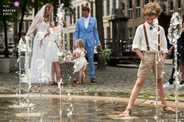 A Breda wedding photographer in the Netherlands captured The son of the newlyweds plays with water when his parents are not watching as He seems to have everything under control