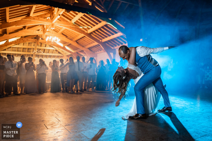 Ein französischer Hochzeitsfotograf im Chateau Montus hat den ersten Tanz von Braut und Bräutigam unter blauem Licht auf der Tanzfläche festgehalten