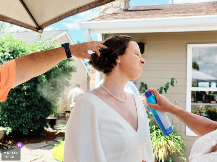 Lake Tapps, WA winning image from the best documentary style wedding photography contest in the world showing The bride gets a sunscreen touch-up during a hot July wedding