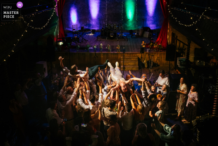 Fotografia di matrimonio in stile editoriale londinese alla Wilton's Music Hall che mostra la coppia inglese che fa crowdsurfing