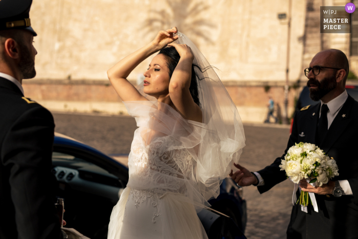 Immagine del matrimonio in stile documentario di Roma dalla Chiesa di Santa Caterina di L'arrivo della sposa davanti alla chiesa nella calda luce del sole