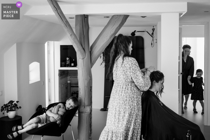 A Netherlands wedding photographer at a Winde home captured the getting ready with a boy at the left, hairdresser in the middle and the bride and her niece at the right side of the picture 