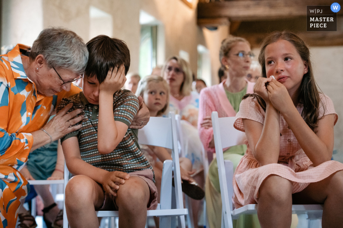 Flandern, Belgien Wettbewerb preisgekrönte dokumentarische Hochzeitsfotografie von der Indoor-Zeremonie, als Kinder der Braut und des Bräutigams während der Gelübde sehr emotional werden und ihre Großmutter versucht, sie zu trösten