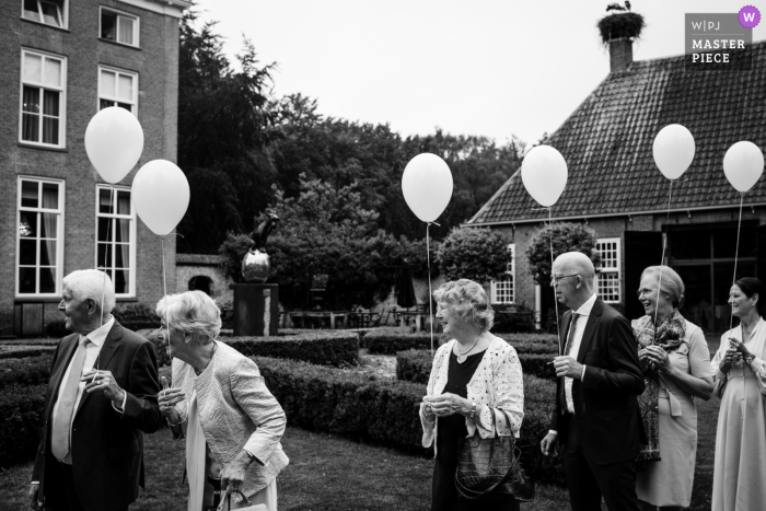 Niederländisches Schwarz-Weiß-Bild vom besten dokumentarischen Hochzeitsfotografie-Wettbewerb der Welt im Havixhorst, das Menschen einfängt, die darauf warten, das Brautpaar zu begrüßen