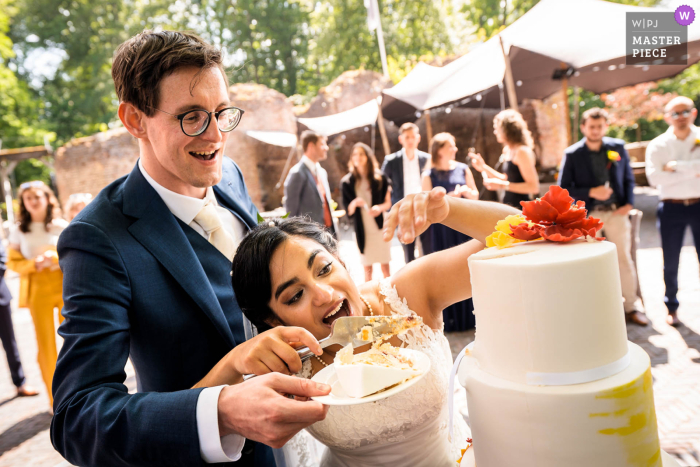 Das Siegerbild des Utrechter Dokumentar-Hochzeitsfotografiewettbewerbs im Schloss Duurstede zeigt, dass das Anschneiden des Kuchens eine Mission ist und die Mission erfüllt wurde