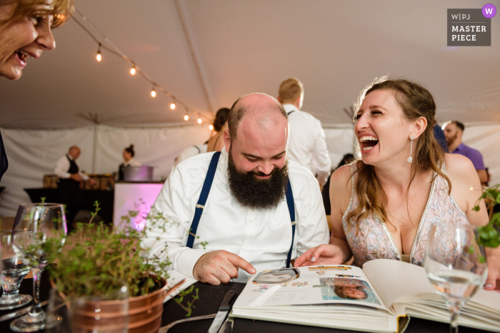 bride and groom looking at scrapbook with old photos prepared by mom Quebec photojournalistic wedding photography at Les Cedres showing a Canadian Bride and groom looking at scrapbook with old photos prepared by mom