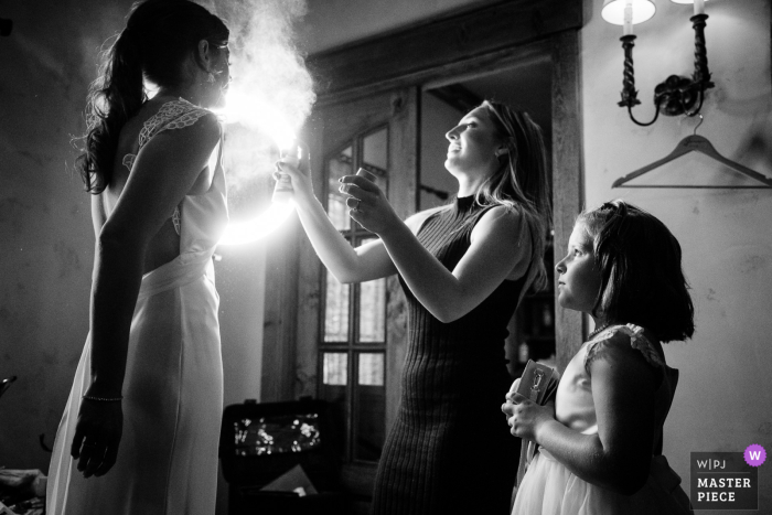 Em uma foto em preto e branco, a daminha e a noiva se preparam para a cerimônia de casamento com um pouco de spray iluminado no rosto Em um momento em preto e branco capturado pelo fotógrafo de Montana, a florista e a noiva se preparam para o grande dia em Manhattan, Montana