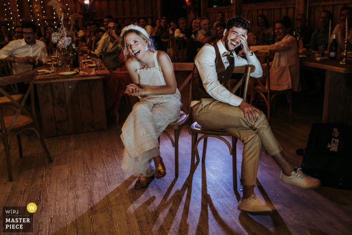 As the couple sits in chairs on the dance floor, nearly back to back, they laugh and enjoy the entertainment at their wedding reception in Toulouse, France