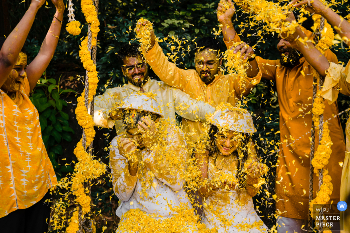 A Haldi ceremony was captured in vibrant, yellow tones as friends threw flowers on the couple An India photographer captured a Haldi ceremony in Karnataka where friends threw flowers on the couple