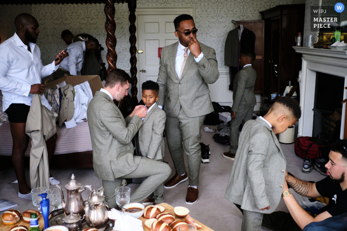 In a busy room, the groomsmen get ready for the wedding, dressed in stylish gray suits At Norwood House in Nottinghamshire, East Midlands, the groomsmen get ready for the wedding, dressed in gray suits