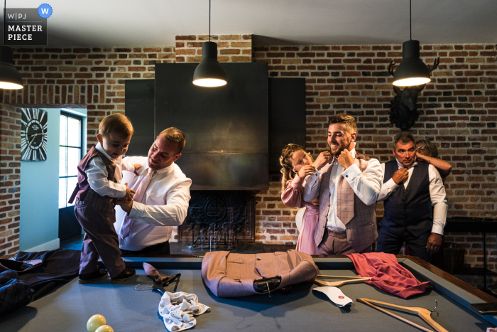 La famiglia si stava preparando per il loro matrimonio, con le cravatte in corso con l'aiuto e il bambino che si vestiva, tutto intorno al tavolo da biliardo La famiglia Ecuries de Sologne si stava preparando per il loro matrimonio, con le cravatte in corso con l'aiuto e il bambino che si vestiva, il tutto circondato dal tavolo da biliardo in primo piano. Questa bella scena è stata catturata dal fotografo francese.