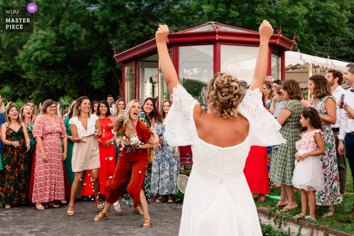 During a New Aquitaine cocktail hour outside the wedding venue, the bridal bouquet toss ends with an exciting catch