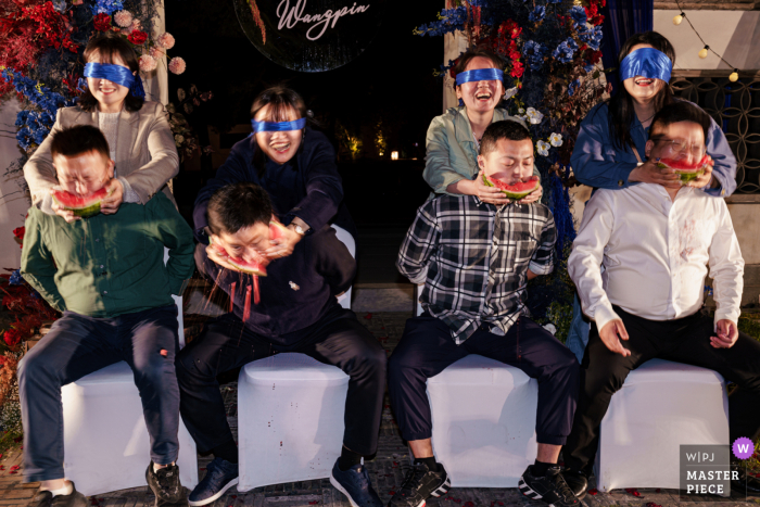 Auf einer Hochzeitsbühne in Shanghai spielen die Gäste das Wassermelonenspiel mit verbundenen Augen