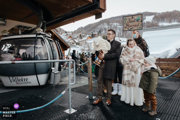 The wedding party was joyfully gathered at the gondola loading location in the picturesque mountainside ski resort Valloire wedding party at the gondola loading location in the mountains