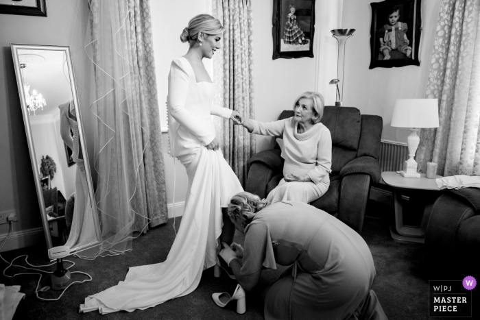 It is time for the final touches of the bridal prep as the bride puts on her shoes, with mum seated watching At the Ashley Park House in Ireland, it is time for bridal prep with mum