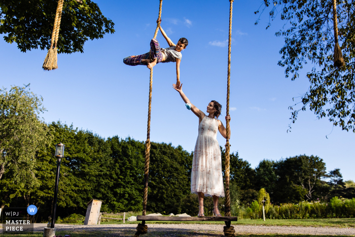 Under a bright blue sky in New England at Primo Restaurant in Rockland Maine, a bride and the officiant play around at a wedding reception