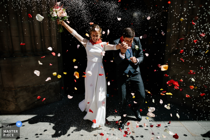 Vista de lanzamiento de pétalos de flores al aire libre desde la Iglesia de San Lorenzo en Pamplona, ​​España de la novia y el novio saliendo de la iglesia en medio de una lluvia de confeti que, afortunadamente, dejó sus expresiones visibles para que todos disfruten