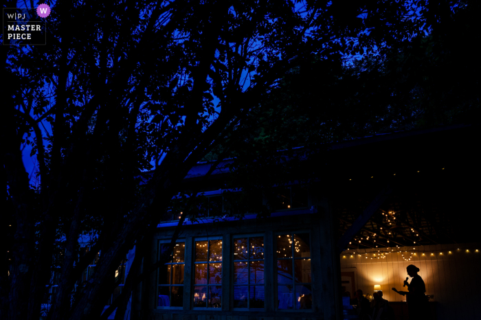 At dusk outside the Lareau Farms of Waitsfield, VT, a bridesmaid can be seen giving a toast during the reception