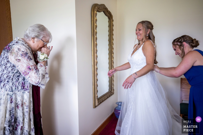 The grandmother's face sparkled with emotion as she beheld her granddaughter for the first time in her wedding dress at the church Before an IL wedding in Chicago at a church, the grandma sees bride for first time in dress