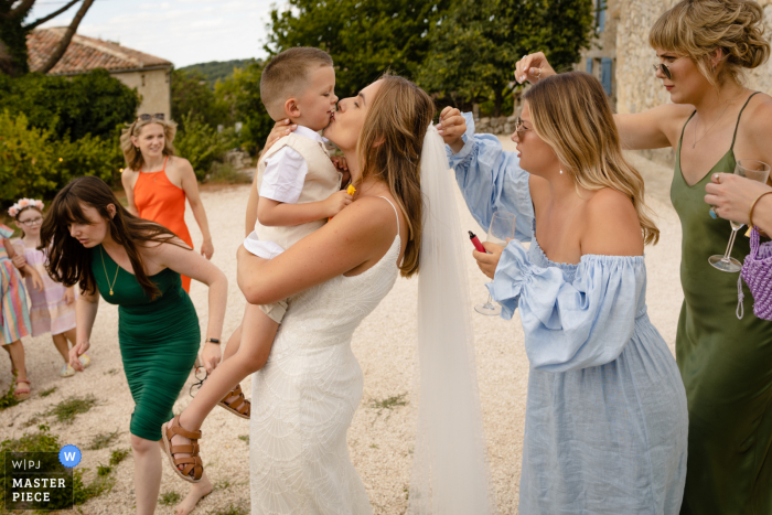  The bride shared a joyous kiss with her godson, surrounded by family and friends in at Lagarde Fieumarcon, Castelnau in Gers, France, with confetti removed from her veil and hair