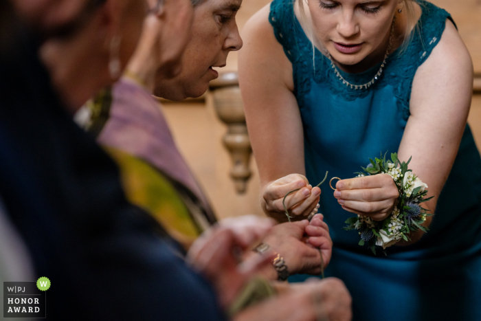 In questa foto scattata a Zugo, in Svizzera, un fotografo di matrimoni cattura un momento speciale mentre tre persone ispezionano da vicino le fedi nuziali in chiesa. Questa immagine ha ricevuto un Honor Award dal WPJA.