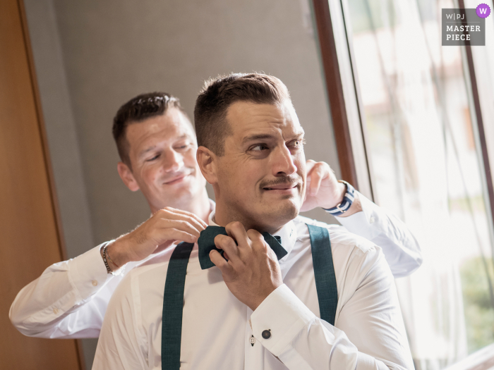 At Villa Bossi in Varese, Italy, capture the frantic moments of the groom's preparations on his wedding day. Photos show the excitement and anticipation of the groom and his tie situation.