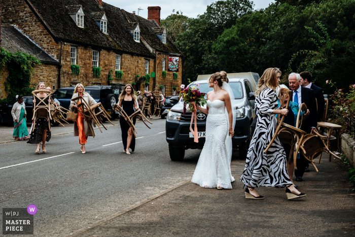 Guests carrying chairs between ceremony and reception locations at Worcestershire, West Midlands