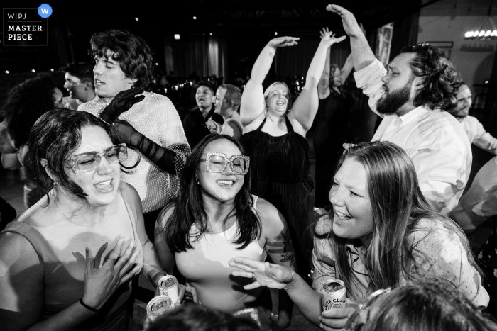Chicago Wedding Guests Let Loose on the Dance Floor in Timeless Black and White Documentary Image This photo captures the energetic atmosphere of a Chicago wedding, with guests dancing and celebrating on the dance floor. The black and white effect adds a timeless and classic touch to the rowdy party scene.