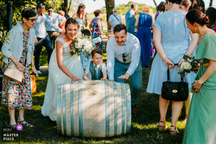Unconventional Wedding Shot: Group Rolling a Barrel at Domaine de la Clausade Mauguio Wedding photo of group rolling a barrel at Domaine de la Clausade Mauguio. Creative use of props adds a unique touch to this shot.