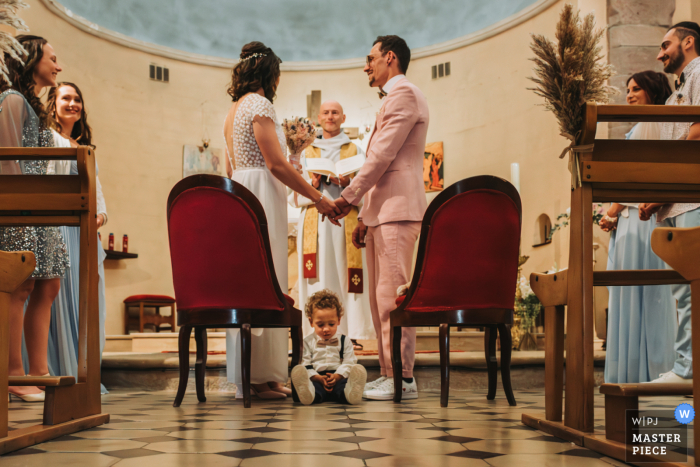PACA Church Becomes Symbol of Love as Newlyweds and Son Receive Blessings in Wedding Photo In this wedding photo, newly married couple receives blessings at a church in Pierrefeu-du-Var, PACA, France as their 2-year-old son sits in between them.