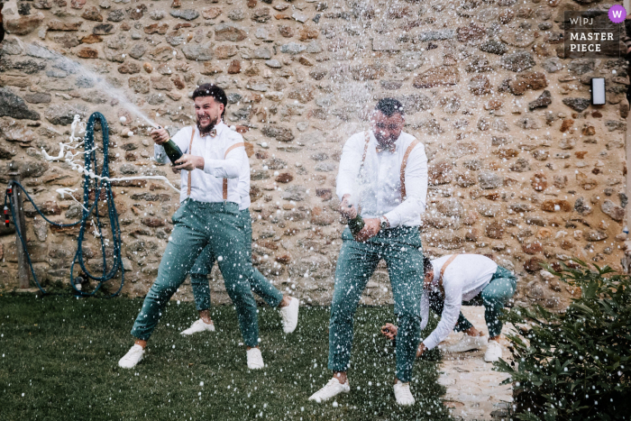 Toasting the Newlyweds with Bubbly in Ardeche, Auvergne-Rhône-Alpes Three wedding guests celebrate the bride and groom's entrance with a spray of champagne at the reception venue in Ardeche, Auvergne-Rhône-Alpes.