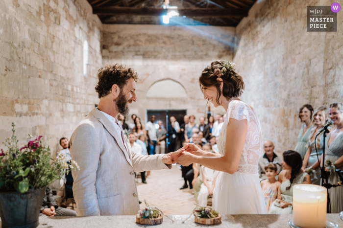 The joyful couple exchange rings at the altar, surrounded by loved ones, in a church in San Quirico, Monferrato.