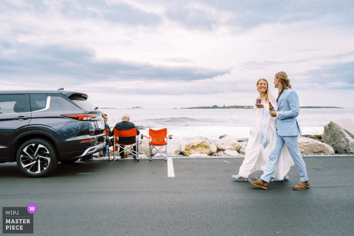 Couple Walks to Wedding Chapel with Ocean View in Boothbay Harbor, ME With the stunning ocean view behind them, the couple takes a romantic walk to their wedding chapel in Boothbay Harbor, ME.