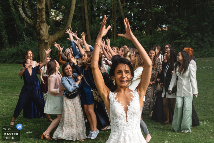 Thrilling Bouquet Toss at Ferme des Templiers in Lille, France | Catching Blooms at a Beautiful Wedding Venue The bride's bouquet toss creates a flurry of excitement as eager hands reach out to catch the blooms at the picturesque Ferme des templiers in Lille, France.