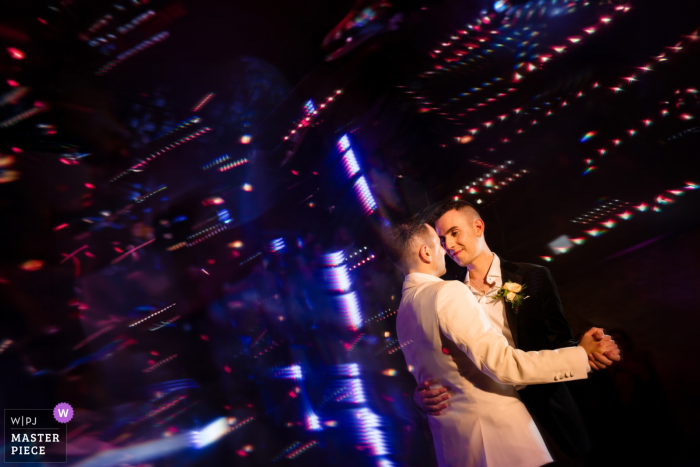 The newlyweds share a first dance at their wedding reception in London, England, surrounded by a dreamy glow.