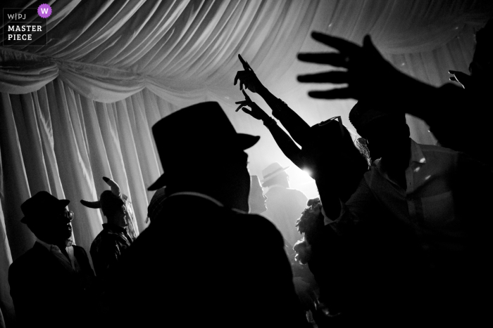 Amidst the grandeur of a London wedding reception, guests celebrate in style under a canopy of drapes creating a beautiful black and white party scene.