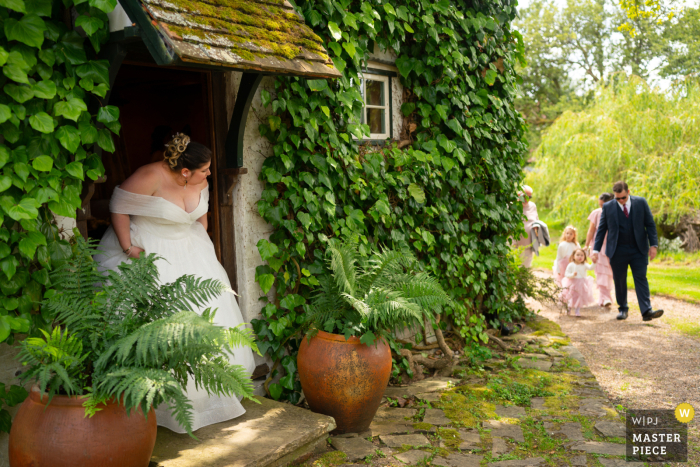 With eager anticipation, the bride awaits the arrival of her flower girls at the picturesque Ridge Farm in Surrey, UK.